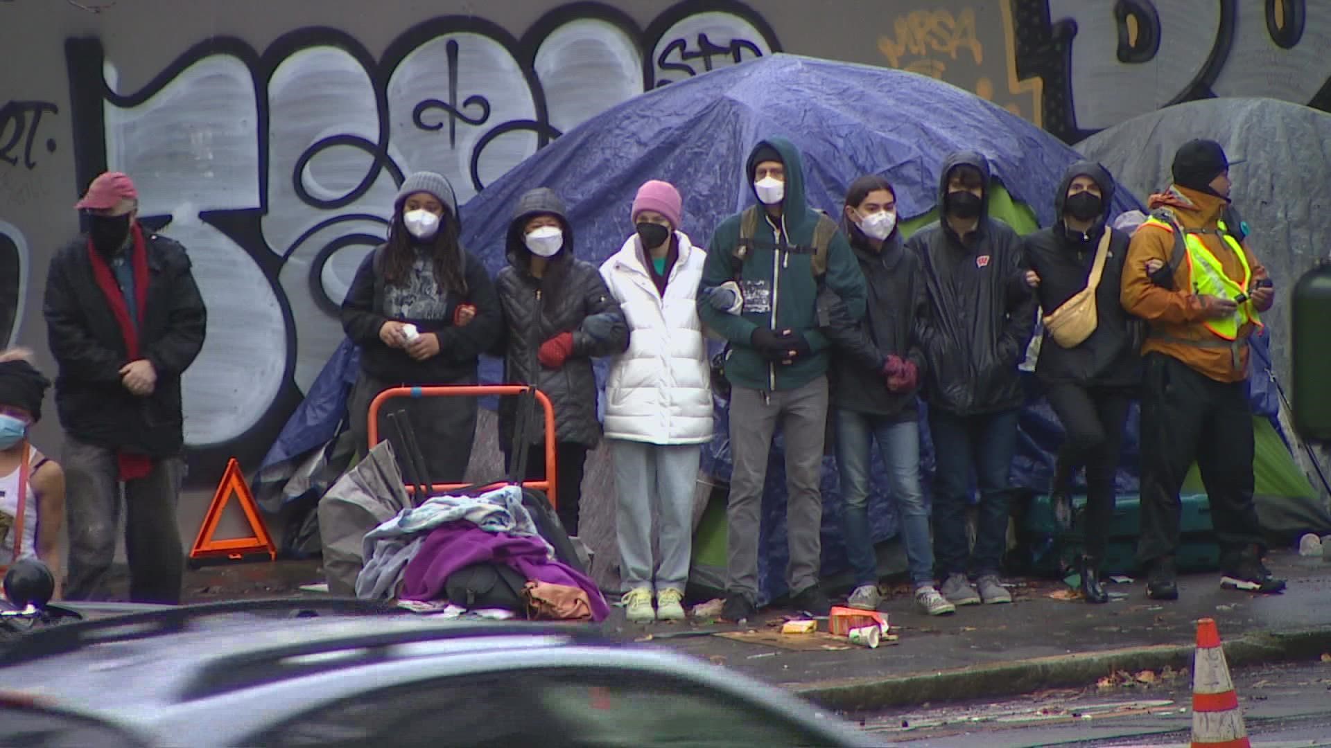 Protestors are trying to prevent city crews from sweeping a homeless encampment across the street from Seattle City Hall.