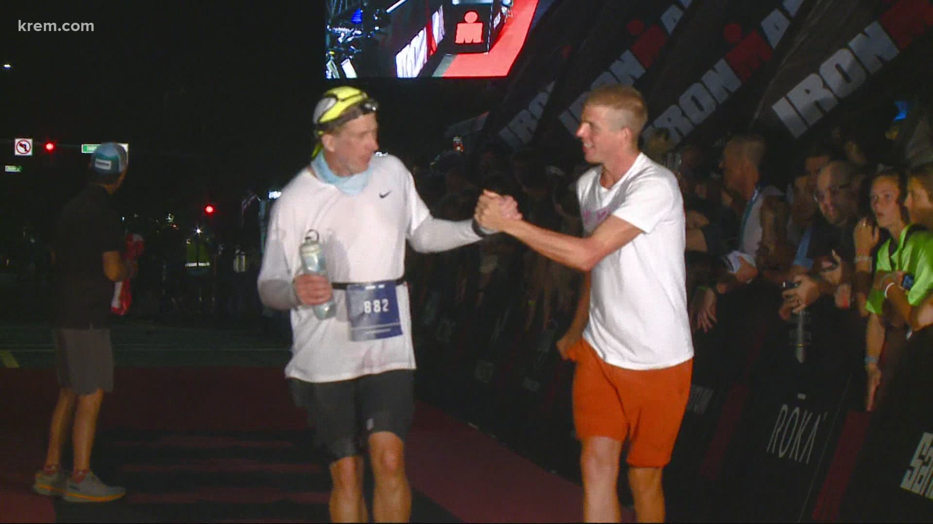 First place winner returns to the Ironman finish line to meet the last athlete as they finish the race