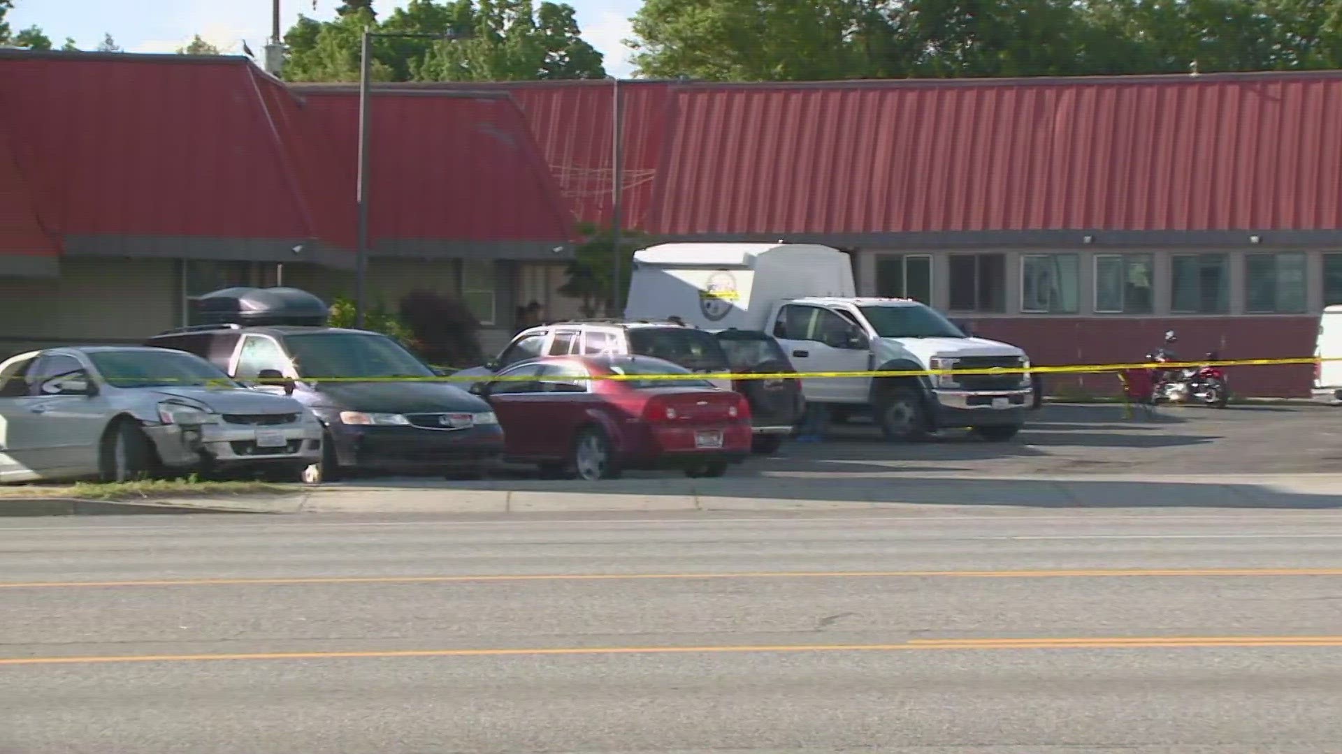 Multiple unmarked police cars are on the scene and yellow crime scene tape is surrounding the motel.